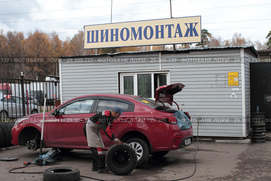 Рабочий шиномонтажа меняет колёса в Балашихе на улице Мира (2018 год). Редакционное фото, фотограф Дмитрий Неумоин / Фотобанк Лори