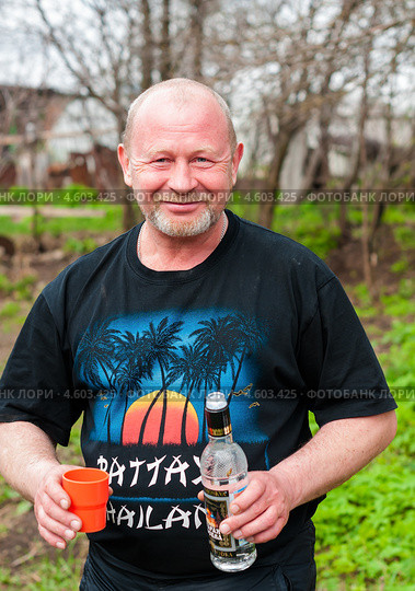 Радостный мужчина с бутылкой водки и стаканом на улице (2013 год). Редакционное фото, фотограф Игорь Низов / Фотобанк Лори