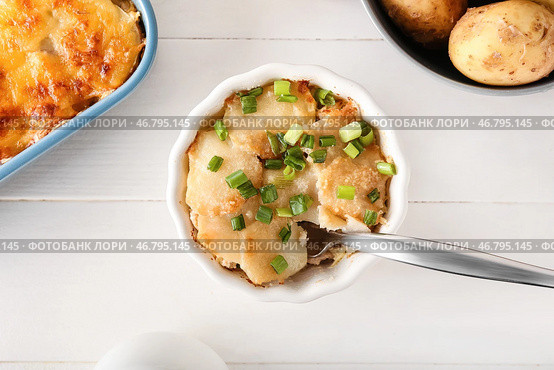 Рамекин с вкусной картофельной запеканкой на светлом деревянном фоне, крупным планом. Стоковое фото, фотограф Pixel_shot / Фотобанк Лори