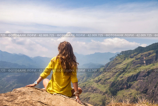 Rear view of lady in yellow jacket sitting at landmark nature background, Sri Lanka, Ella. From behind of woman enjoy at landscape Adam's peak mountain. Summer vacation concept. Copy ad text space. Стоковое фото, фотограф Aleksandr Golubev / Фотобанк Лори