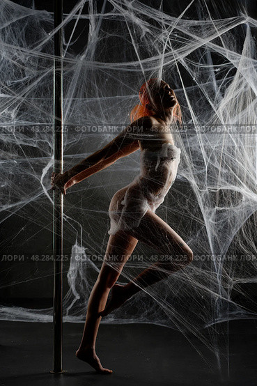 Red-clad woman entangled in a net trap amidst a dark, web-like backdrop. Стоковое фото, фотограф Гурьянов Андрей / Фотобанк Лори