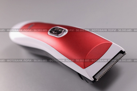 Red hair clipper on a gray background. Choosing a quality hair machine concept. Red hair clipper on a gray background. Стоковое фото, агентство Ingram Publishing / Фотобанк Лори