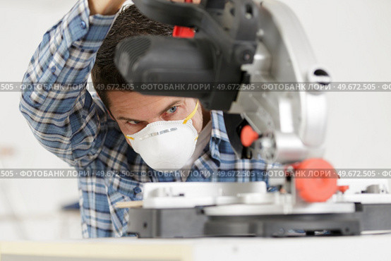repairman standing with electric saw in mask. Стоковое фото, агентство Ingram Publishing / Фотобанк Лори