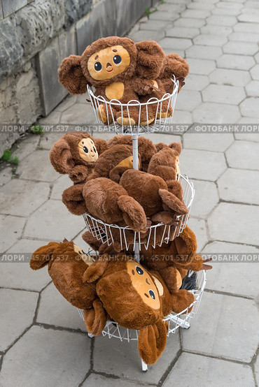 Resort town Kislovodsk, Stavropol Krai, Russia: March 27, 2023: Soft plush toys Cheburashka in basket in front of store on street. Редакционное фото, фотограф Алексей Антипов / Фотобанк Лори