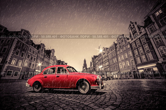 Retro red car on cobblestone historic old town in rain. The market square at night. Wroclaw, Poland.. Retro red car on cobblestone historic old town in rain. Wroclaw, Poland. Стоковое фото, агентство Ingram Publishing / Фотобанк Лори