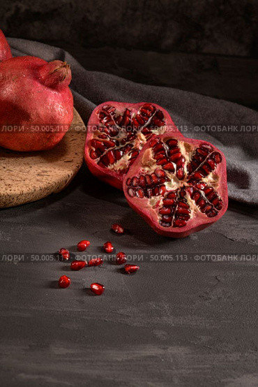Ripe pomegranate fruit and pomegranate seeds on dark background, close-up. Healthy vegetarian antioxidant organic diet food. Стоковое фото, агентство Ingram Publishing / Фотобанк Лори