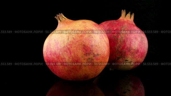 Ripe pomegranate fruit with leaves on black background. Стоковое фото, агентство Ingram Publishing / Фотобанк Лори