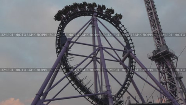 Rollercoaster Loop, Amusement Park, Ride: Thrill-seeking passengers experience a large loop on a purple rollercoaster during daytime. Стоковое видео, видеограф svetograph / Фотобанк Лори