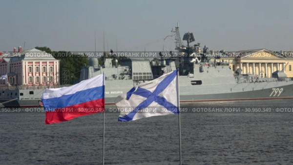 Российский и Андреевский флаги на фоне фрегата "Адмирал Макаров". День ВМФ в Санкт-Петербурге (2018 год). Редакционное видео, видеограф Виктор Карасев / Фотобанк Лори
