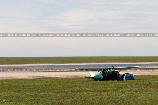 Россия, Калмыкия. 04.20.2019: Легкомоторный самолет Cessna 182 Skylane стоит в цветущей степи на берегу озера. Редакционное фото, фотограф Ольга Шуклина / Фотобанк Лори