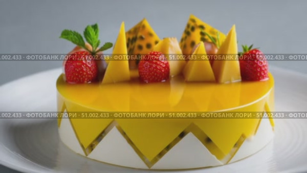 Rotating mango cake decorated with fresh fruits on white background. Стоковое AI-видео, аниматор Юрий Поздников / Фотобанк Лори