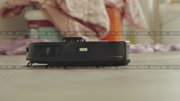 round robot vacuum moves methodically across the bathroom floor, its sensors scanning for dust and hair. Стоковое видео, видеограф Feruza Tashmetova / Фотобанк Лори