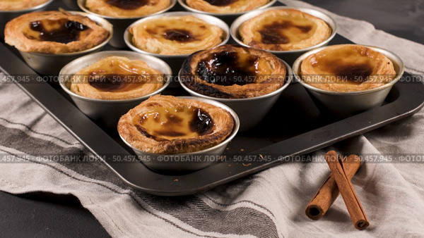 Rows of freshly cooked egg tarts, traditional portuguese dessert, pastel de nata, custard tarts on metal tray. Стоковое фото, агентство Ingram Publishing / Фотобанк Лори