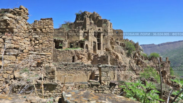 Ruins of ancient Gamsutl village with abandoned building stone walls on mountain slope cliff against blue sky on sunny day in Dagestan Russia (2021 год). Стоковое видео, видеограф Алексей Кузнецов / Фотобанк Лори