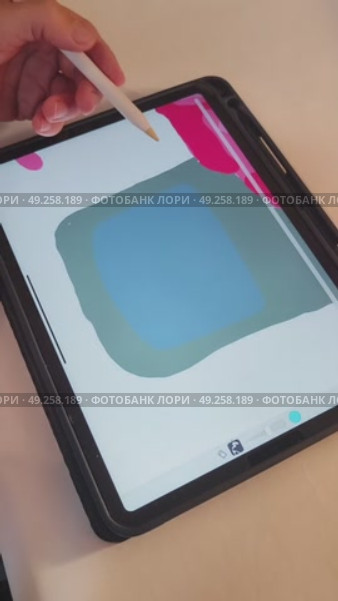 Рука девушки креатора держит в руке пальцами pensil и рисует на планшете ipad pro изображение цветка красной розы в стакане в специальной программе для обучения художников для инстаграм и тик ток. Редакционное видео, видеограф Светлана Русских / Фотобанк Лори
