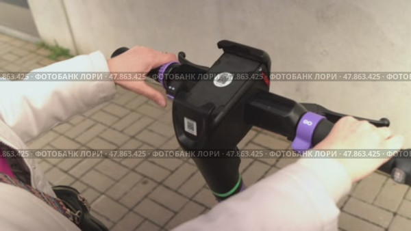 Russia, Sosnovy Bor, April 18, 2025 - Woman unlocking and locking an electric scooter with smartphone. Редакционное видео, видеограф Андрей Знаменский / Фотобанк Лори