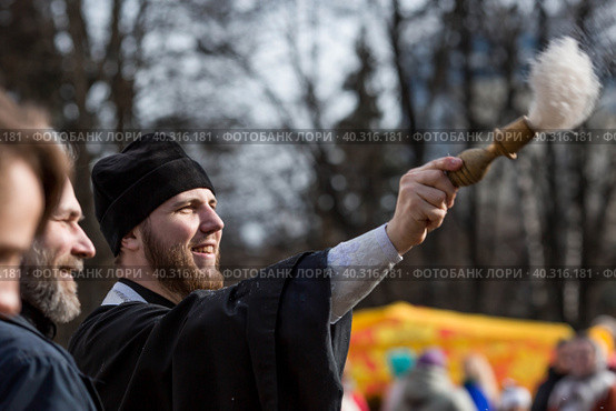 Russia, the City of Vidnoye, April 15, 2023. Easter service. The priest sprinkles people and Easter treats with holy water at the entrance to the temple. People go to sanctify eggs and cakes. Редакционное фото, фотограф Photojuli / Фотобанк Лори
