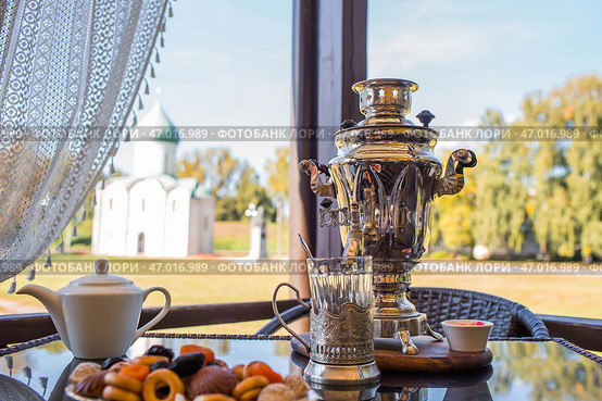 Russian traditions. Tea drinking over a samovar. Still life with bagels and Russian treats on the veranda against the background of the Transfiguration Cathedral in Pereslavl-Zalessky. Стоковое фото, фотограф Photojuli / Фотобанк Лори