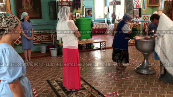 Russian women are on toddler baptism in church, godmother with goddaughter, mother with teenager daughter. Ceremony of sacrament of initiation into the Christian (2021 год). Редакционное видео, видеограф Кекяляйнен Андрей / Фотобанк Лори