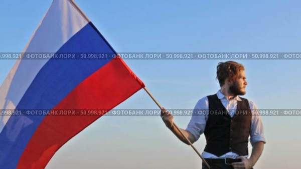 Русский мужчина с российским флагом на фоне неба. Стоковое видео, видеограф 1Andrey Милкин / Фотобанк Лори