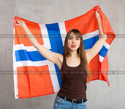 Sad young woman holding flag of Norway against unicoloured background. Стоковое фото, фотограф Яков Филимонов / Фотобанк Лори