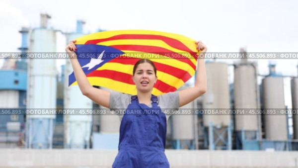 Sad young woman worker standing with big flag of Catalonia against background of factory. Стоковое видео, видеограф Яков Филимонов / Фотобанк Лори