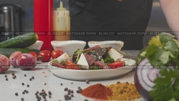 Salad, garnished with scattering of sesame seeds, is laid out on kitchen table amidst array of vegetables and salad components. Стоковое видео, видеограф Strunov David / Фотобанк Лори