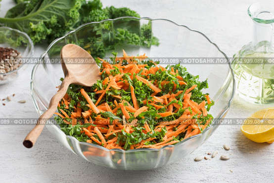 Salad with kale, carrots and seeds in a transparent salad bowl on a light gray background. Стоковое фото, фотограф Ольга Лепёшкина / Фотобанк Лори