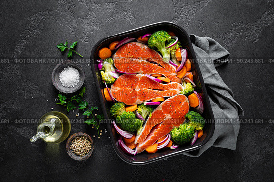 Salmon. Cooking fresh raw salmon fish steaks with vegetables, broccoli, carrot and onion on black background, top view. Стоковое фото, агентство Ingram Publishing / Фотобанк Лори