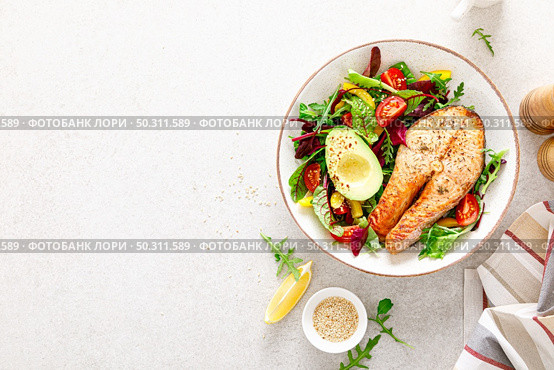 Salmon fish steak grilled, avocado and fresh vegetable salad with tomato, bell pepper and leafy vegetables. Top view. Стоковое фото, агентство Ingram Publishing / Фотобанк Лори