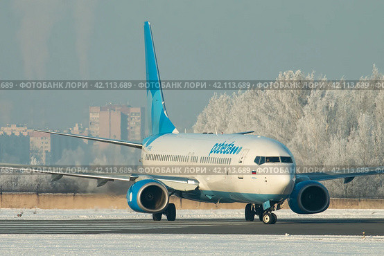 Самолет Boeing 737-800 авиакомпании Победа на рулении в аэропорту Пулково зимой, на фоне покрытого белым инеем леса (2019 год). Редакционное фото, фотограф Сергей Крамарев / Фотобанк Лори