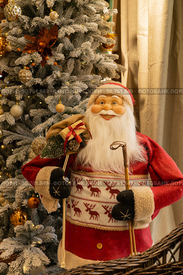 Santa Claus doll in a wicker basket on the background of the Christmas tree. Стоковое фото, фотограф Оксана Шведкова / Фотобанк Лори