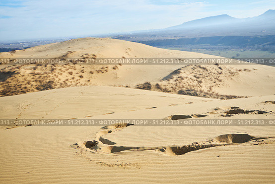 Sarykum dune, the largest sand dune in Europe.. A desert scene with a large mound of sand. The sand is dry and the sun is shining brightly. Стоковое фото, фотограф Наталия Кирсанова / Фотобанк Лори