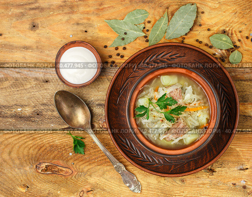 Sauerkraut soup is a traditional dish of Russian, Ukrainian or Polish cuisine. Kapustnyak. Soup with beef, potatoes, onions, cabbage, parsley and spices. Selective focus, top view. Стоковое фото, фотограф Виктория Панченко / Фотобанк Лори