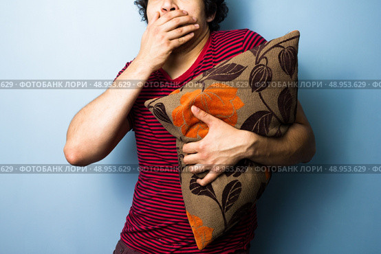 Scared young man clutching a cushion. Стоковое фото, агентство Ingram Publishing / Фотобанк Лори