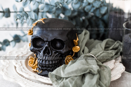 Scary black skull with golden roses and pumpkins on serving plates for a Halloween or Day of the Dead party. Стоковое фото, фотограф Photojuli / Фотобанк Лори
