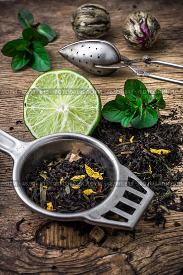 scattered on wooden table tea leaves and tea strainer.Selective focus. tea leaves. Стоковое фото, агентство Ingram Publishing / Фотобанк Лори