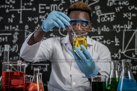 Scientists mixing yellow chemicals in glass at the laboratory. Стоковое фото, агентство Ingram Publishing / Фотобанк Лори