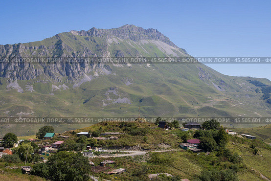 Село Верхний Кани, Республика Северная Осетия — Алания, Россия. Северный Кавказ. Вид на поселение на фоне гор. На переднем плане жилые дома и хозяйственные постройки горного села. Вдали гора Хиах, Скалистый хребет, Кавказские горы. Стоковое фото, фотограф Андрей Степанов / Фотобанк Лори