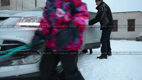 Семья прогревает и очищает автомобиль от снега перед зимней поездкой, дети помогают. Стоковое видео, видеограф Кекяляйнен Андрей / Фотобанк Лори