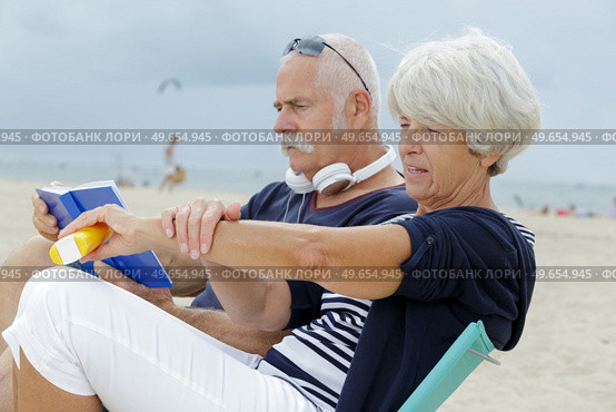 senior couple on the beach woman applying suncream. Стоковое фото, агентство Ingram Publishing / Фотобанк Лори