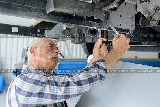 senior mechanic checking underneath vehicle. Стоковое фото, агентство Ingram Publishing / Фотобанк Лори