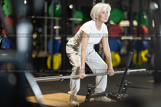 Senior woman performing deadlifts with barbell at gym. Стоковое фото, фотограф Яков Филимонов / Фотобанк Лори