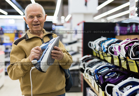 senor man pensioner buying iron in showroom of electrical appliance store. Стоковое фото, фотограф Татьяна Яцевич / Фотобанк Лори