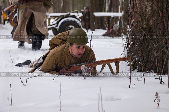 Sestroretsk, Russia - February 19, 2023: Soldiers reenact winter combat, skillfully maneuvering in deep snow while staying in tactical positions, echoing historical strategies. Редакционное фото, фотограф Aleksandr Golubev / Фотобанк Лори