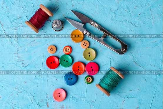 Set of  pied buttons for garment with threads on blue background. Colorful plastic buttons. Стоковое фото, агентство Ingram Publishing / Фотобанк Лори