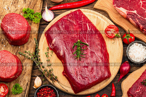 Set of various steaks with traditional spices and herbs. Fresh raw meat cuts includes ribeye, eye round, flank and striploin steaks. Old wooden background, flat lay, top view. Стоковое фото, агентство Ingram Publishing / Фотобанк Лори