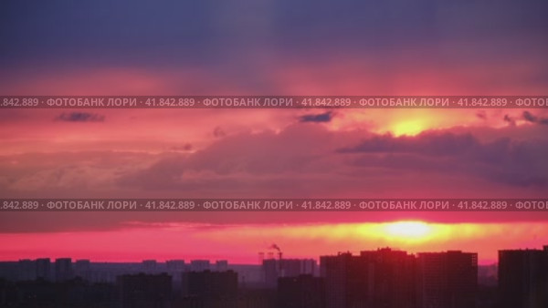 Setting evening sun behind the silhouettes of buildings. Nightfall in the big city, timelapse. Top view of the city at dusk. Стоковое видео, видеограф Андрей Журавлев / Фотобанк Лори