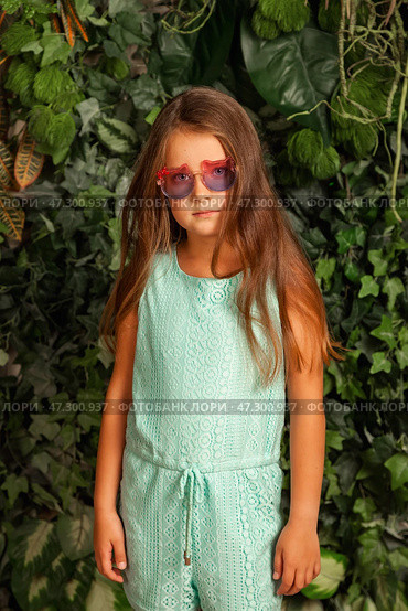 Seven Year Old Girl Model Poses With Confidence in a Green Outdoor Setting Wearing Stylish Glasses. Стоковое фото, фотограф Aleksandr Golubev / Фотобанк Лори