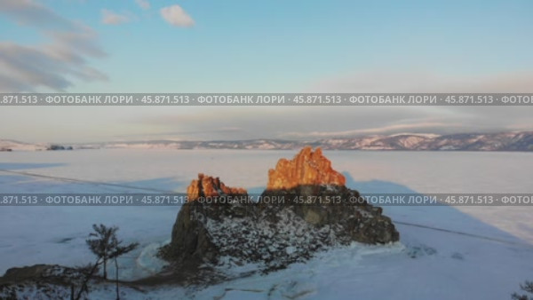 Shamanka Rock or Cape Burkhan at dawn in winter. Frozen Lake Baikal in the snow. Aerial view. Стоковое видео, видеограф Виктория Тельминова / Фотобанк Лори